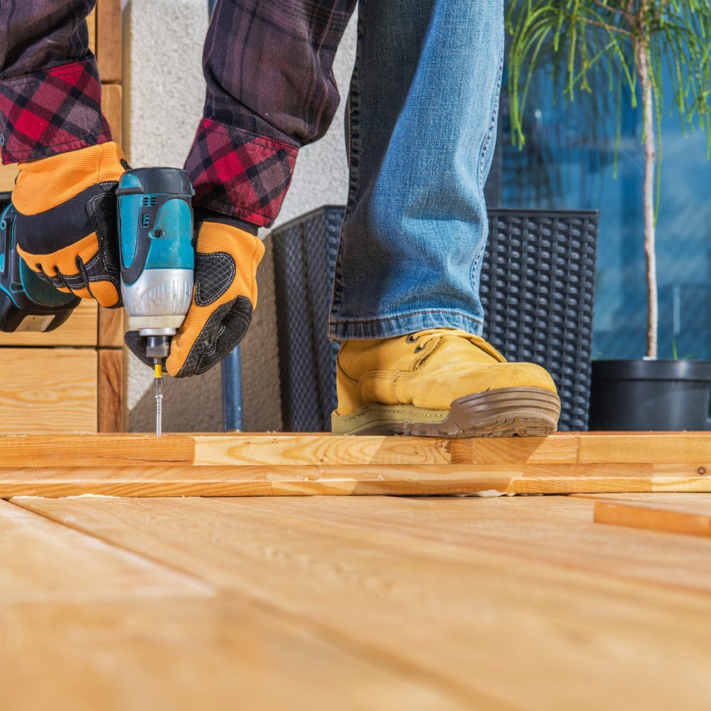 Men Building Wooden Porch Attaching Wood Planks Elements with Large Screws Using Cordless Driver. Small Wooden Garden Project