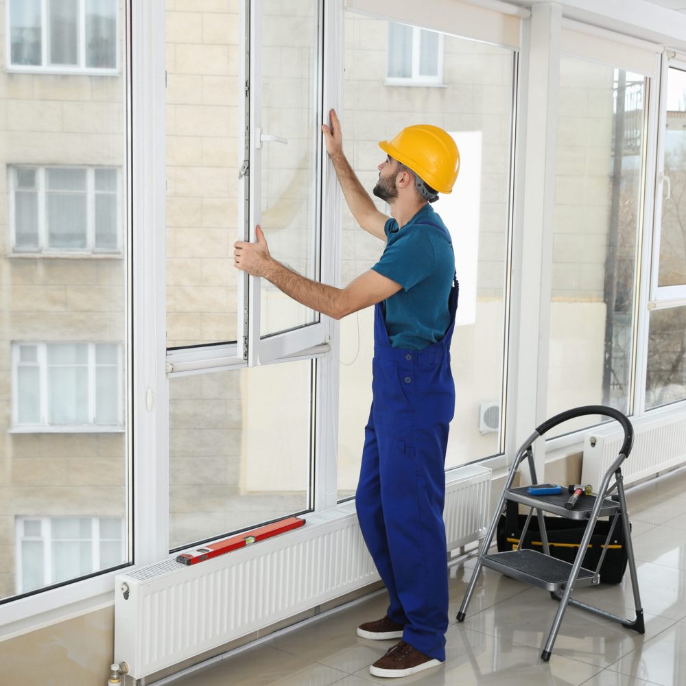 Construction worker installing plastic window in house