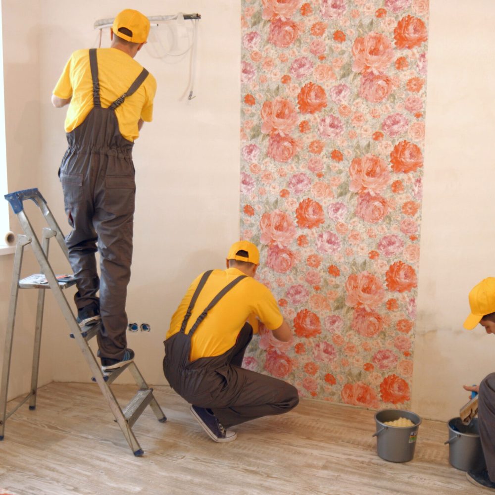 Brigade of builders hang wallpaper in the apartment. Contractor repairing apartments. Home improvement concept.