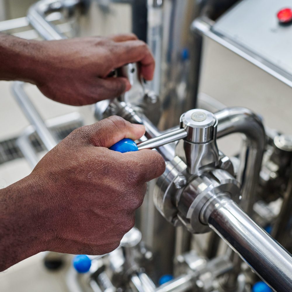Close-up of African American worker turning levers on pipe to control the equipment